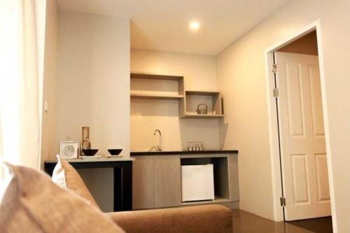 a living room with a couch and a kitchen at Dancenter Sukhumvit 107 Bangkok Hotel in Bangkok