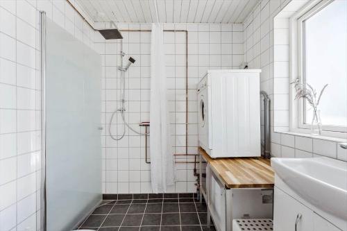 a white tiled bathroom with a shower and a sink at 8217-Vordingborg-Kvaedevej-10 in Vordingborg
