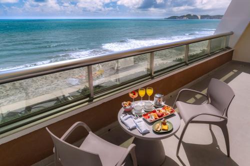a table with food on a balcony with the beach at Serhs Natal Grand Hotel & Resort in Natal
