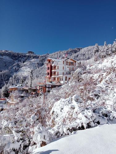 a building on the side of a snow covered mountain at The Mountain Palace Kufri By Exotic Stays in Kūfrī