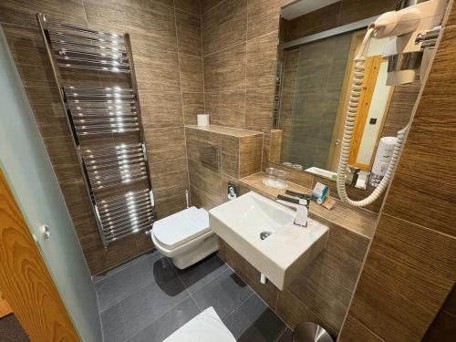 a bathroom with a sink and a toilet and a mirror at Hotel Pieris in Vysoke Tatry - Podbanske