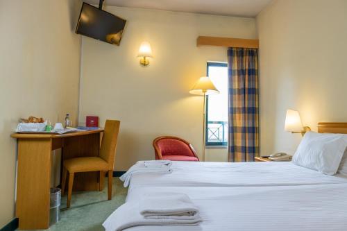 a hotel room with two beds and a desk at Flag Hotel Guimarães Fafe in Fafe