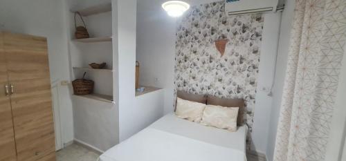 a small bedroom with a white bed and a wall at Appartement s1 hamamet in Hammamet