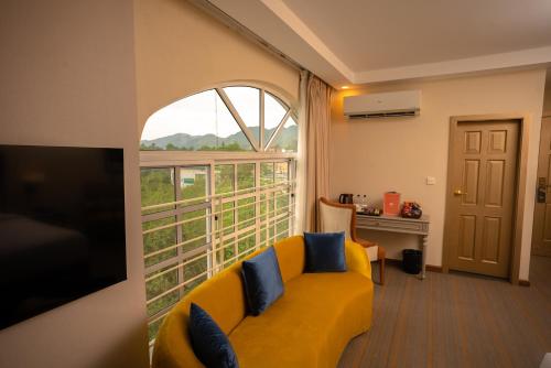 sala de estar con sofá amarillo y ventana grande en Cityscape Rooms & Suites, en Islamabad
