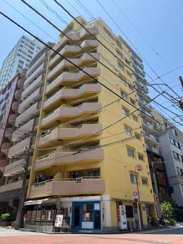 a tall yellow building with balconies on a street at Tokyo Shinjuku Mia in Tokyo