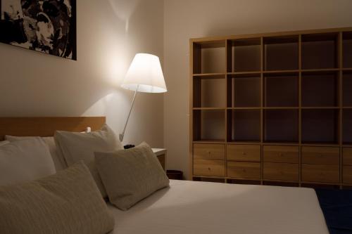 a bedroom with a bed with a lamp and a dresser at Portopiccolo Apartments in Sistiana