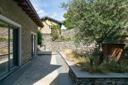 a walkway in front of a stone building with a tree at Via del Pontile in Nesso