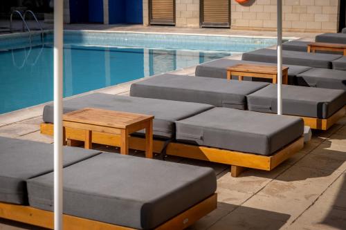 a row of lounge chairs next to a swimming pool at Stephanos Hotel Apartments in Polis Chrysochous