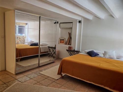une chambre avec deux lits et un miroir dans l'établissement Charmante maison de ville, à Grasse
