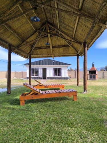 a group of benches under a pavilion with a building at Cabañas Willy Azul con pileta climatizada y parque en Mendoza in Las Compuertas