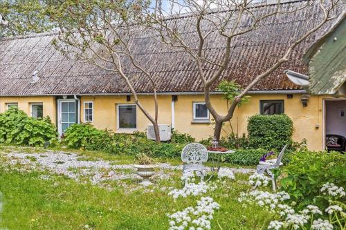 a yellow house with a yard with a bench and flowers at 4320-Stege-Oddermose-Strandvej-5-B in Stege