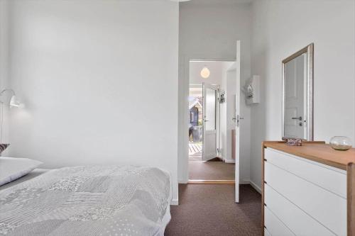 a white bedroom with a bed and a mirror at 8205-Vordingborg-Strandparken-12 in Vordingborg
