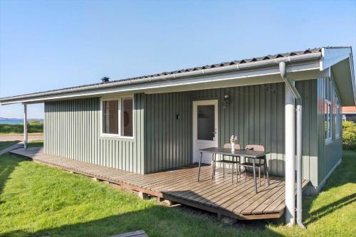 a green house with a wooden deck and a table at 8205-Vordingborg-Strandparken-12 in Vordingborg