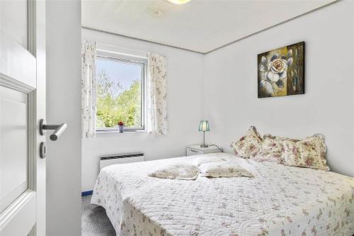 a white bedroom with a bed and a window at 1305-Stege-Kaerhogevej-29 in Stege