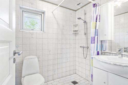 a white bathroom with a toilet and a sink at 1305-Stege-Kaerhogevej-29 in Stege