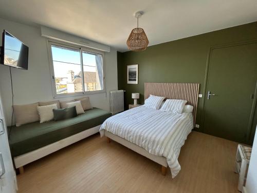 een slaapkamer met een bed, een bank en een raam bij Ty Fanch Quiberon in Quiberon