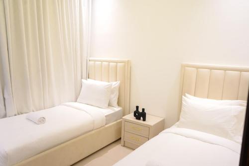 two beds in a bedroom with white walls and white pillows at Al Dana Sea Luxury Villa Fujairah in Sharm