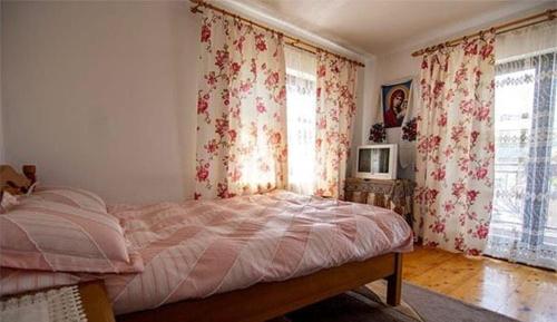 a bedroom with a bed and two windows with curtains at Casa Morarului in Bîrsana