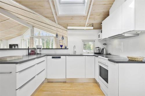 a kitchen with white cabinets and a wooden ceiling at 3304-Stege-Kvaerken-42 in Stege