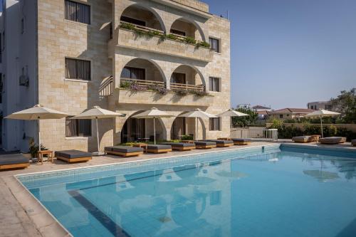 a swimming pool in front of a building with umbrellas at Stephanos Hotel Apartments in Polis Chrysochous