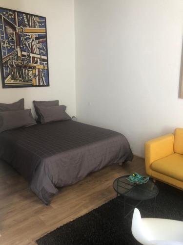 a bedroom with a bed and a yellow chair at Studio Anna centre historique Bordeaux St Pierre in Bordeaux