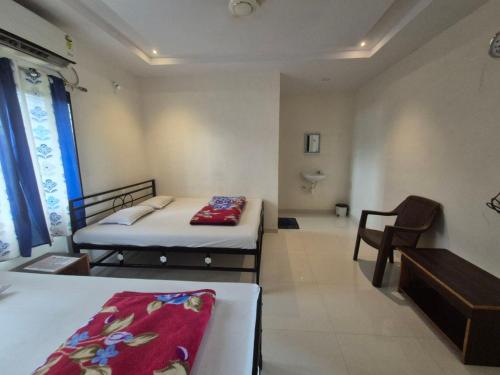 a room with two beds and a chair in it at Gurucharan in Shirdi