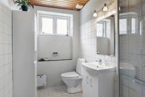 a white bathroom with a toilet and a sink at 4259-Stege-Fabriksgade-14 in Stege