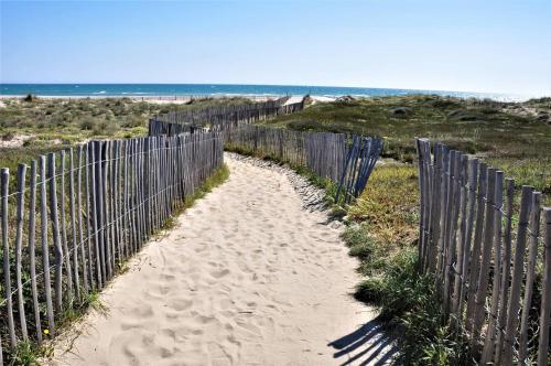 a fence on the beach next to a fenceasteryasteryasteryasteryasteryasteryastery at Maison de vacances moderne et pratique : WiFi, clim, parking et cour privée in Canet-en-Roussillon