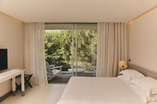 a bedroom with a bed and a sliding glass door at Hôtel Plage Palace & Spa in Palavas-les-Flots