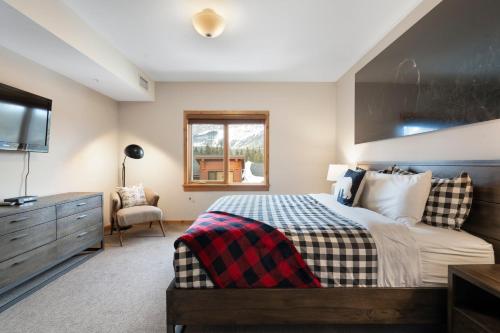 a bedroom with a bed and a dresser and a window at Spring Creek Penthouse by Canadian Rockies Vacation Rentals in Canmore