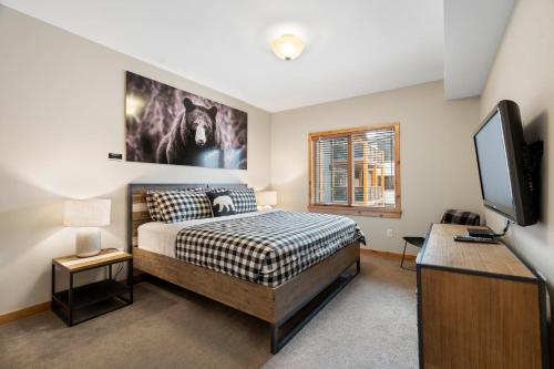 a bedroom with a bed and a flat screen tv at Spring Creek Penthouse by Canadian Rockies Vacation Rentals in Canmore