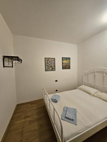 a white bedroom with a bed and two pictures on the wall at Ca' San Valentino in Pontelongo
