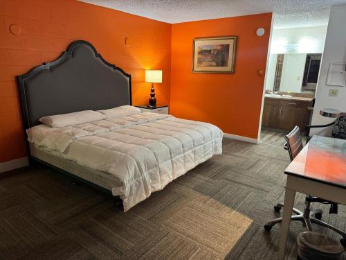 a bedroom with orange walls and a large bed at Capri Motel By Belvilla Walla Walla US 12 in Walla Walla