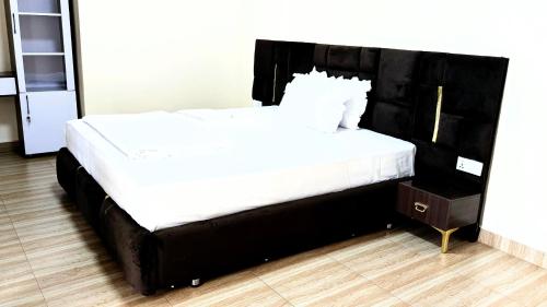 a large bed with a black headboard and white sheets at Kigali Great Garden in Kigali