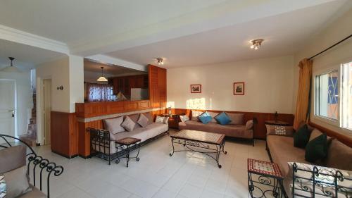 a living room with a couch and a table at Maison dans espace calme, avec piscine et plage à quelques minutes à pied in Aourir