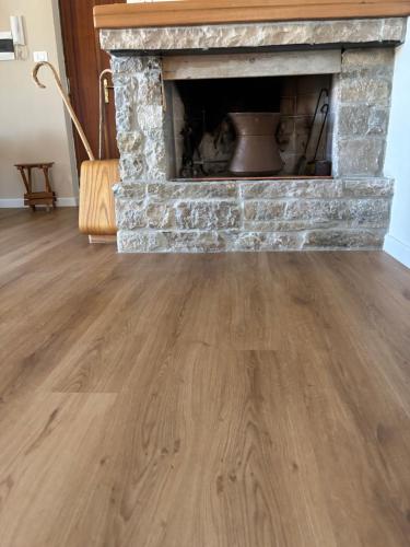 a living room with a stone fireplace and wooden floors at Rame! in Agnone