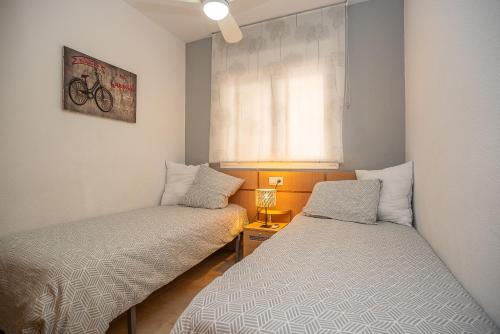 a small room with two beds and a window at JARDINES DEL MAR II Vitamina D todo el año entre playa y montaña in El Borseral