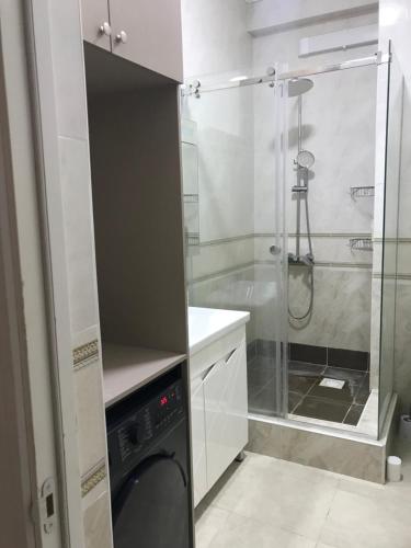 a bathroom with a shower and a washing machine at Уютный уголок в престижной части города 3 in Bishkek