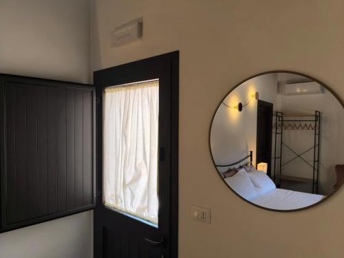 a bedroom with a mirror next to a bed and a window at Agriturismo Travaglianti Alloggio Etna in Ragalna