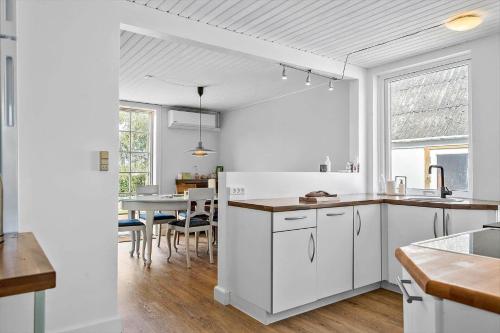 a kitchen with white cabinets and a dining room at 4019-Stege-Udbyvej-15 in Stege