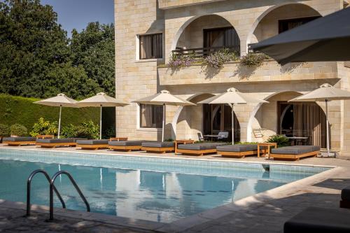 a pool with chairs and umbrellas next to a building at Stephanos Hotel Apartments in Polis Chrysochous