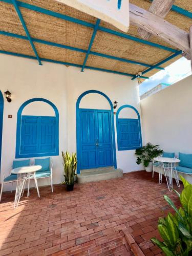 a patio with blue doors and tables and chairs at Homestay Văn Vĩnh Hy 4 in Vĩnh Hy