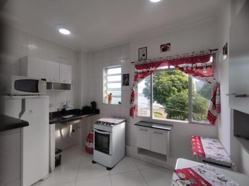 a small kitchen with white appliances and a window at Prainha apto 202 in São Vicente