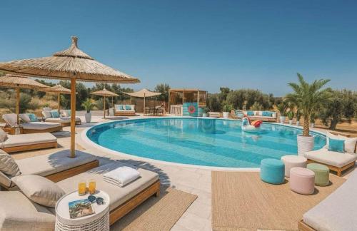 a swimming pool with chairs and umbrellas at a resort at Seven stars Camping Evelina in Keratea