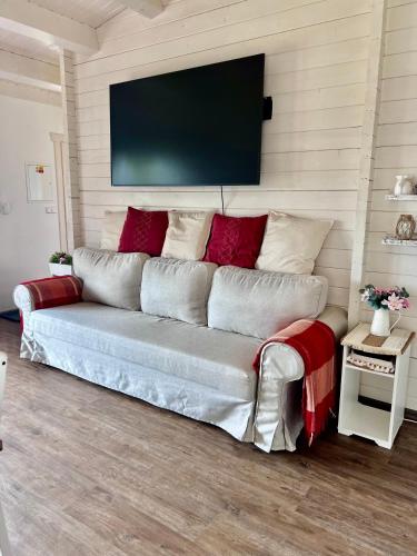 a living room with a couch with a television on the wall at Log cabins at Iron Rose in Czech Canada in Nová Bystřice