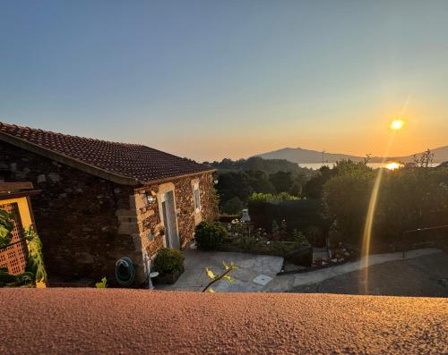 a stone house with a sunset in the background at Casa da Avó Quina - Seixas in Coura