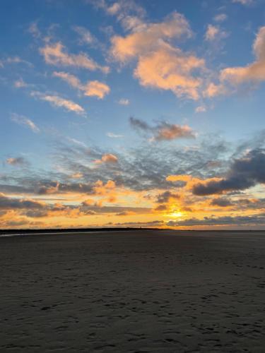 a sunset over the ocean with a cloudy sky at Strandhuisje Anna dicht bij de zee in Ouddorp