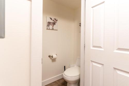 a white bathroom with a toilet and a door at Alpine Village Condo by Canadian Rockies Vacation Rentals in Canmore