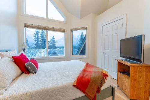 a bedroom with a bed and a flat screen tv at Alpine Village Condo by Canadian Rockies Vacation Rentals in Canmore