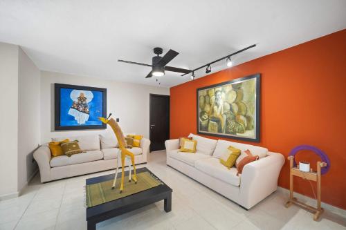 ein Wohnzimmer mit zwei weißen Sofas und einer orangefarbenen Wand in der Unterkunft ALTABRISA Casa Familiar en Merida in Mérida